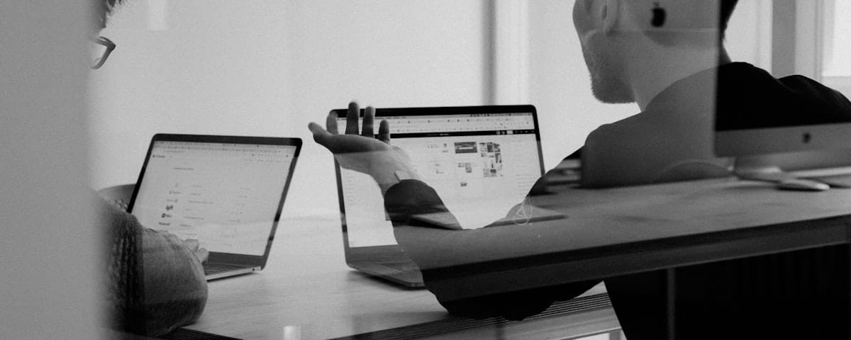 Dwoje przedsiębiorców planuje strategię SEO i budżet marketingowy przy laptopie w jasnym biurze